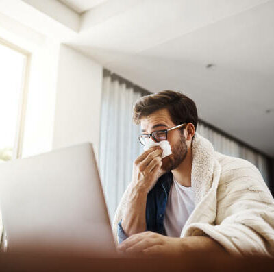 istockphoto-1135911892-612x612 Shot of a sickly young businessman blowing his nose with a tissue while working from home